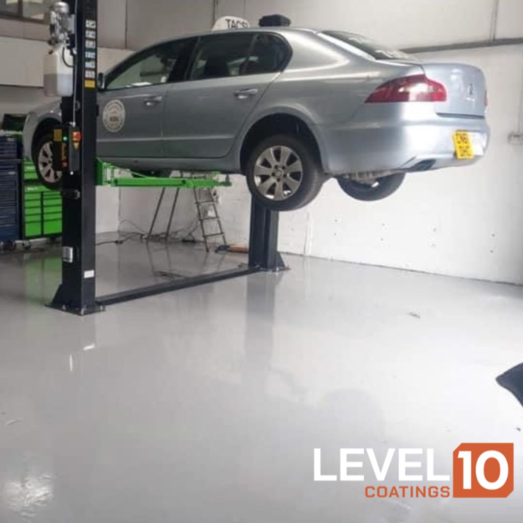 Car elevated on a lift within a well-maintained service center featuring durable coated floors.
