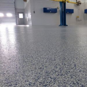 Vibrant blue epoxy floor in an automotive shop, customized to match the shop's branding colors.