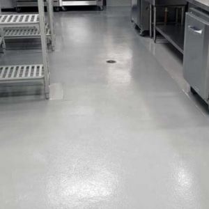 Dark gray polished concrete floor in a busy commercial kitchen.